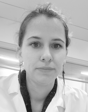 Black and white photo of a woman with earrings, wearing a lab coat.