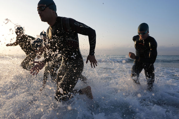 Triathlon athletes charge out of the water.