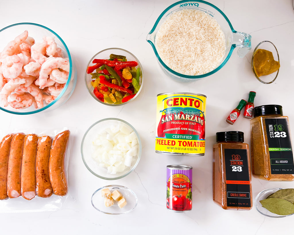 a mise en place of all ingredients before cooking - shrimp, sausage, bell pepper, onion, garlic, canned san marzano tomatoes, tomato paste, better than bouillon chicken base, bay leaves, and Station 1923 Creole Smoke and All Aboard seasonings