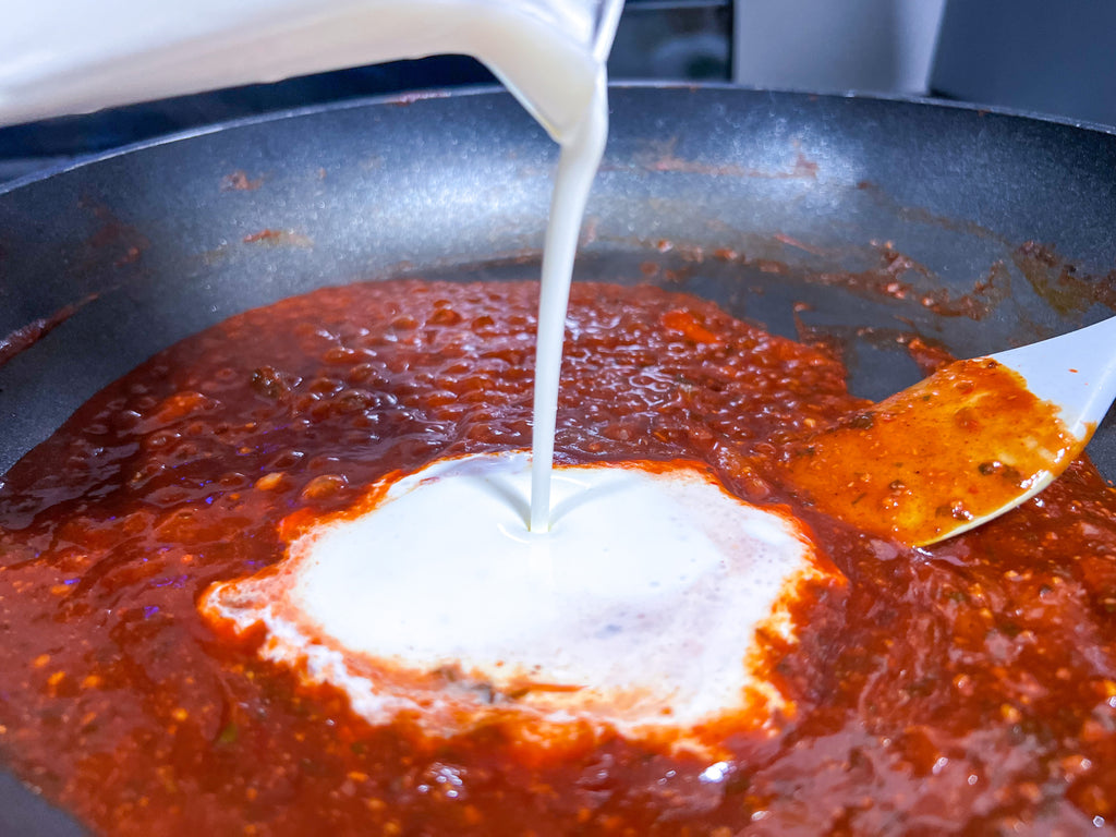 pouring heavy cream into the reduce guajillo tequila lime sauce