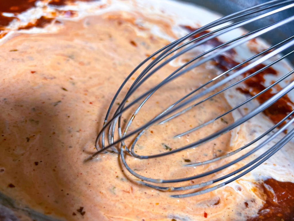 whisking together heavy cream and guajillo tequila lime sauce ingredients