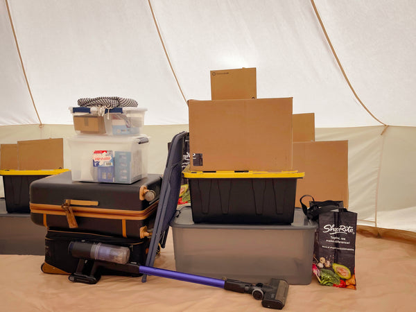 Une pile de boîtes et de bacs à l'intérieur d'une tente de stockage en toile.