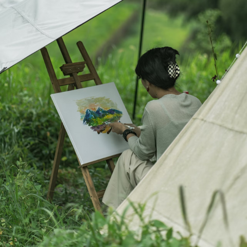 woman painting outside of canvas tent
