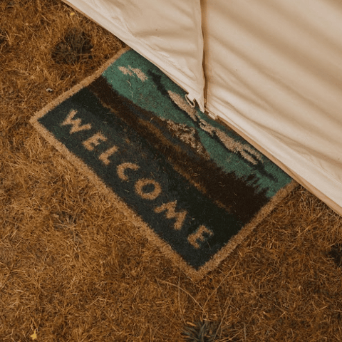 a welcome mat outside a canvas bell tent