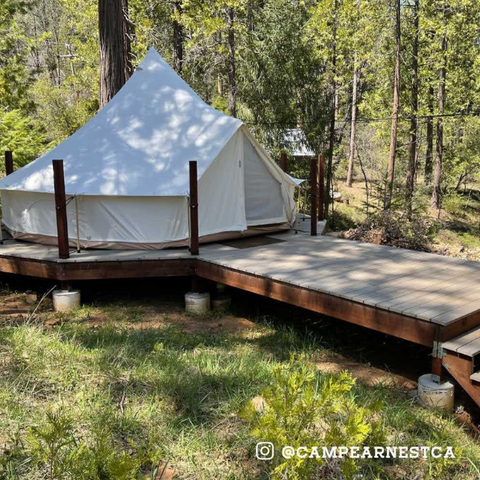 white canvas bell tent house on wood platform