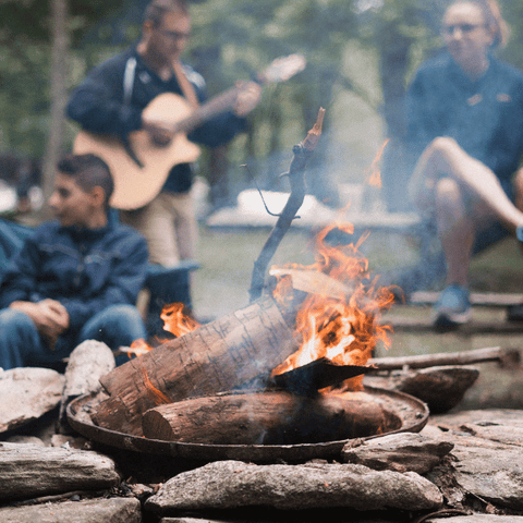 feu de camp avec des campeurs en arrière-plan