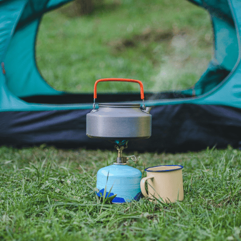 cuisinière et bouilloire à l'extérieur de la tente de camping