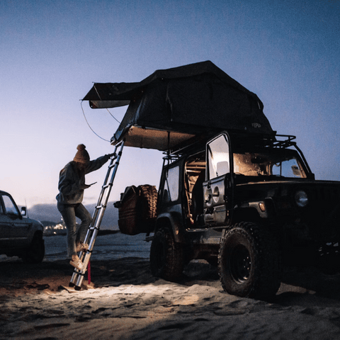 Tienda de campaña de raíz en jeep con escalera.