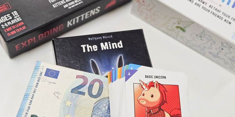 collection of affordable card games under 20 eur, usd with a 20 eur bill on top of one of the games