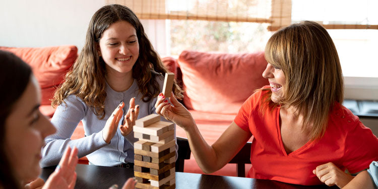 a family with teenage kids having a board game night by playing jenga