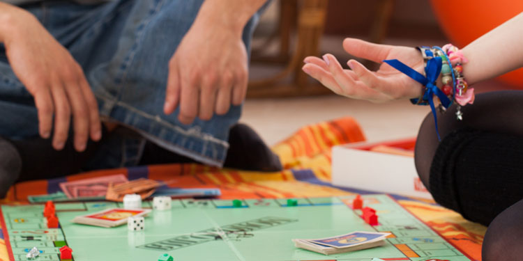 a parent with his teenage kid playing monopoly board game