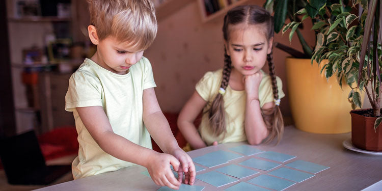 two small children are playing with a simple memory based board game for ages 4 and up