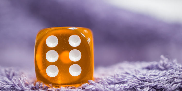 close up of an orange d6 rolling die, the number six is shown to the camera