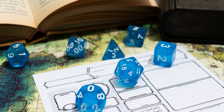 a collection of blue rolling dice on a game board, an opened book seen in the background