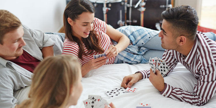 a group of friends playing cards on the bed