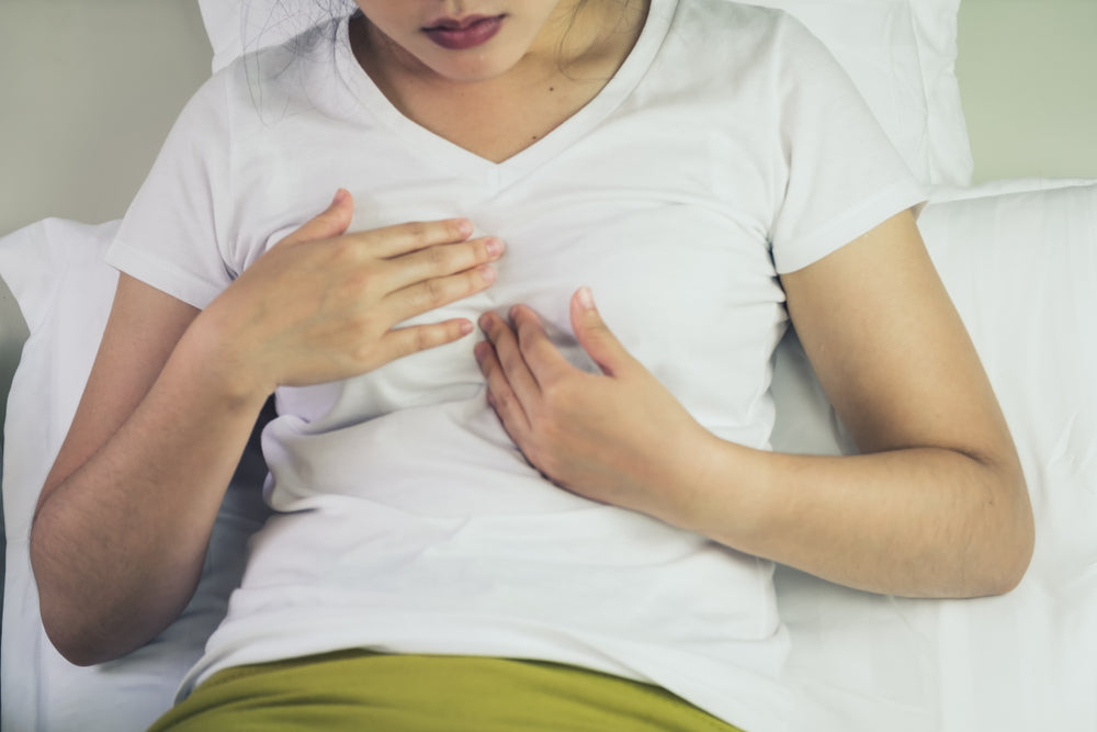 woman holding chest with acid reflux pain