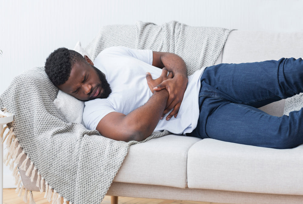 man laying on couch with heartburn pain