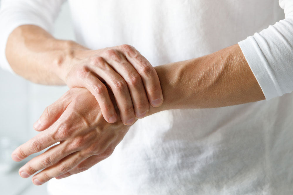 man suffering from arm numbness holding wrist