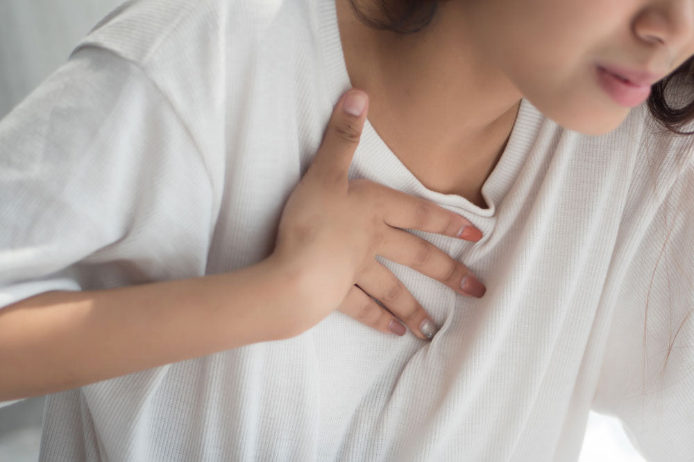 woman holding chest with reflux pain