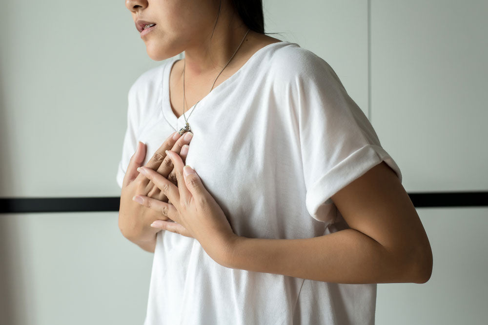 woman holding chest from GERD pain 