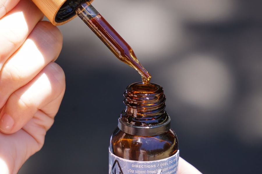 Hand lifting a dropper from a CBD oil bottle