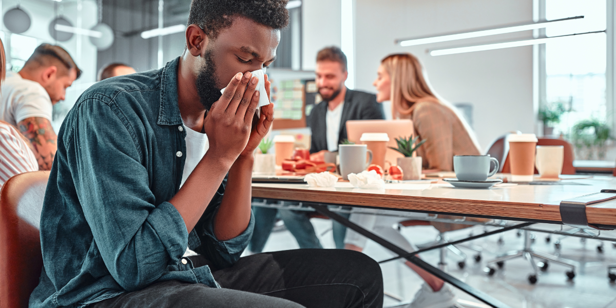 Man blwoing his nose in the office