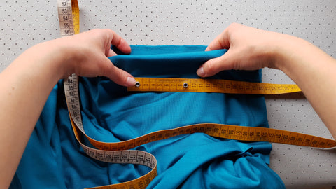 A photo showing how to perform the fabric stretch test with the use of a tailor measuring tape.