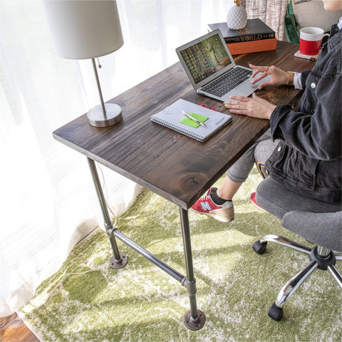 Close-up image of a desk with efficient organization, featuring a laptop, notebook, and lamp, supported by a PIPE DECOR® frame, in a cozy, sunlit corner.