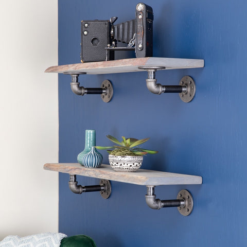 Image of two distressed wood floating shelves on a blue wall, adorned with a vintage camera, stylish vases, and a potted plant, enhancing a cozy and artistic home decor theme.