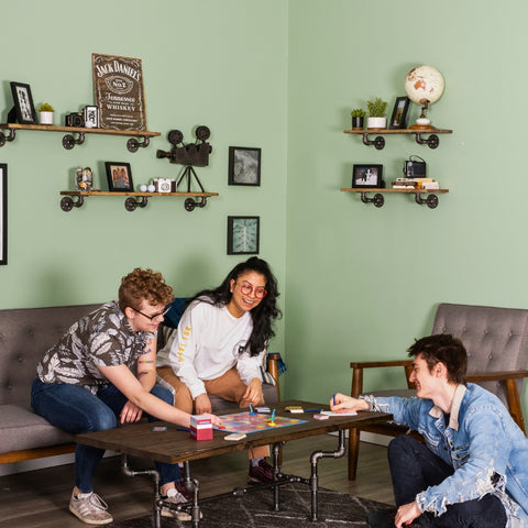 A fun-filled living room featuring whimsical decor and friends enjoying a game, highlighted by industrial pipe furniture that adds a touch of unique charm and practicality.