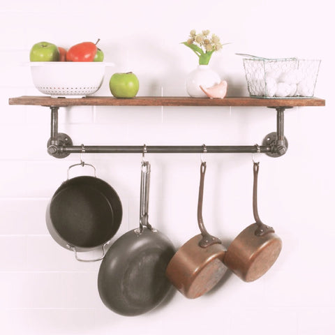 A rustic kitchen setup featuring a PIPE DECOR® shelf with hanging pots, fresh apples, and decorative items, perfect for adding functional style to any home.