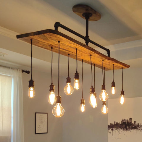 Image of an elegant PIPE DECOR® pendant light featuring multiple Edison bulbs suspended from a wooden beam, adding a warm, industrial charm to the room.