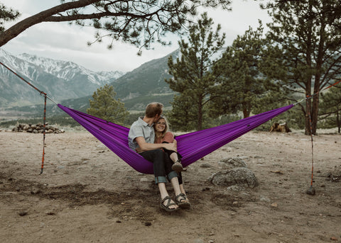 Man and woman hanging out in Roo Double hammock with mountain backdrop