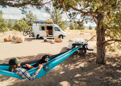 Man hanging in Roo Double at campsite with camper van in background.