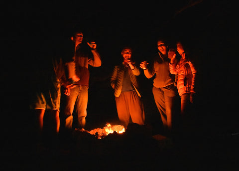 five friends gathered around a campfire at night.