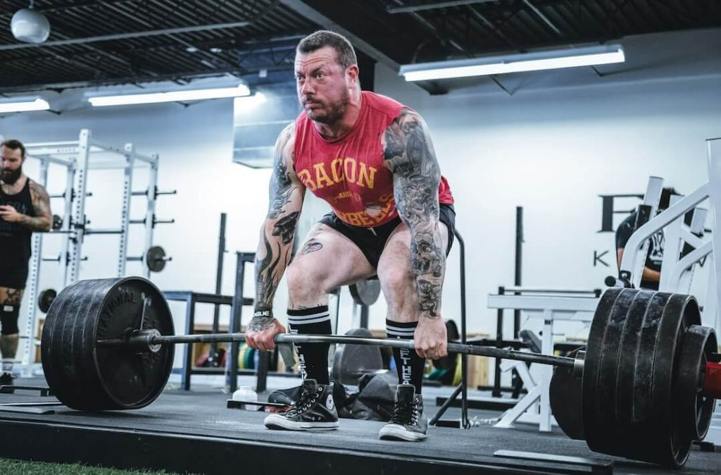 deadlifting barbell with arm sleeve tattoo
