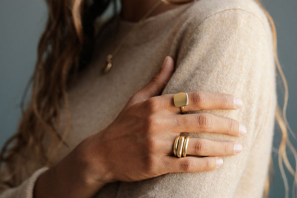 Woman in cashmere wearing solid 18k gold George Rings