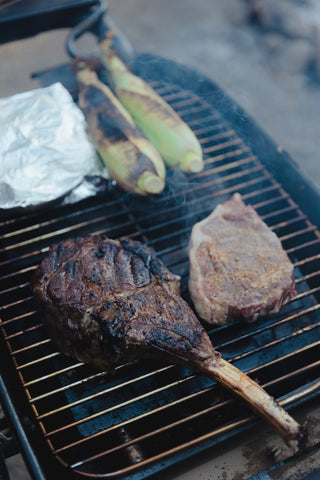 Tomahawk on grill with steak and corn