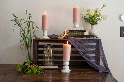 Pink pillar candles sitting on white ceramic candleholders