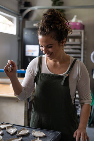 Woman brushing details onto handmade ceramic pottery pieces