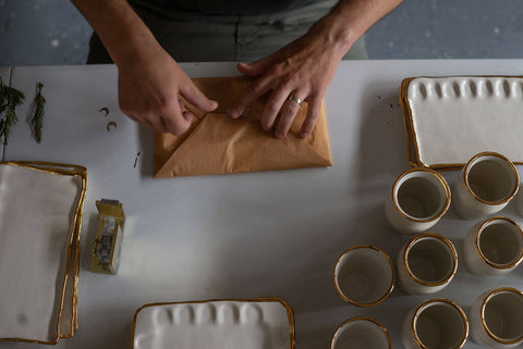 Person wrapping homemade ceramic pottery piece at their small business in Seattle