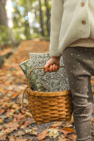 Petite fille tenant un panier avec des papiers peints à l'intérieur