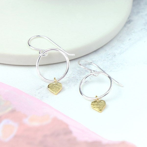 These solid Sterling Silver hoop earrings are attached to fine silver hooks and they ooze a modern elegance. Suspended from each hoop is a scratched heart which is plated in a contrasting golden finish. We love the fact the heart can move freely around the hoop creating a sense of movement.   Size - approx. hoop size 12mm, heart 5mm.
