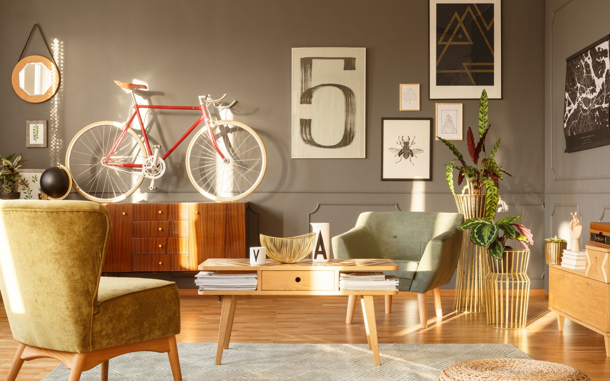 Salon retro z drewnianymi podłogami, komodą, vintage rowerem, oraz plakatami dekoracyjnymi