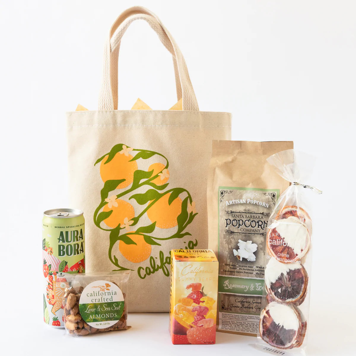 Tote bag with oranges and the word California, containing popcorn, gummy bears, almonds, dried oranges and a drink