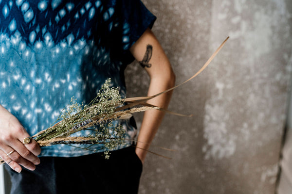 Indigo dyed top on a woman holding wheat and flowers