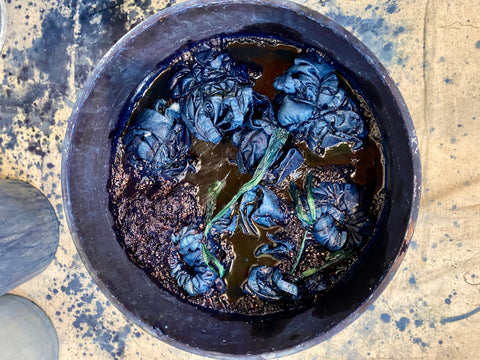 bucket of indigo dye with pieces of fabric in it