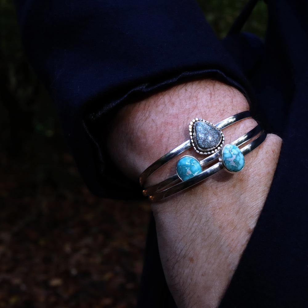 Three turquoise and sterling silver cuffs worn on arm in pocket