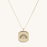 Gold pendant with sun rising above the horizon