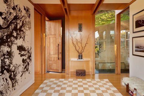 Wood paneled entryway with a wood door and tan checkered jute rug